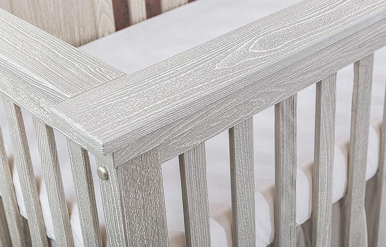 Close-up of solid wood crib rail and slats showing the wood grain