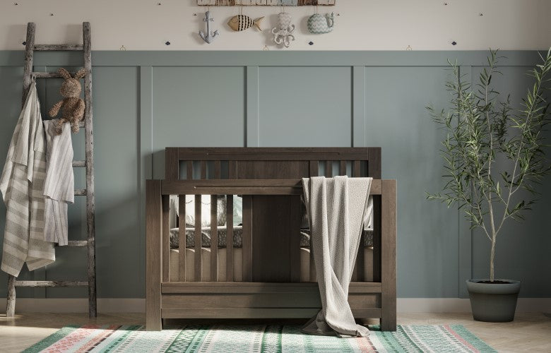 Dark wood solid hardwood convertible crib in a nursery with sage green paneled walls