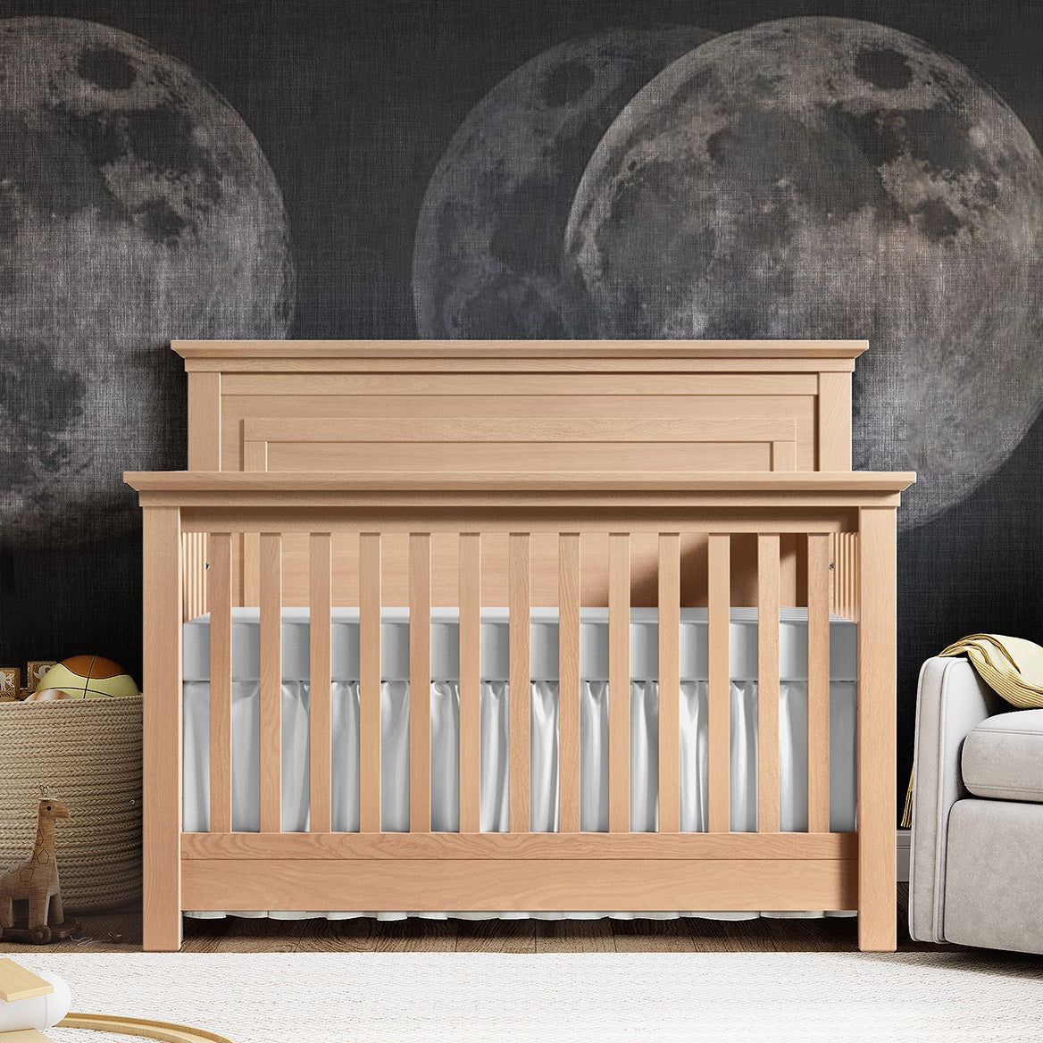 Nursery with wooden crib, gray bedding, and moon-themed wall decor.